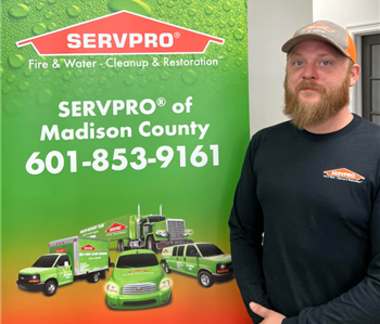Male employee in black shirt standing in front of a SERVPRO sign